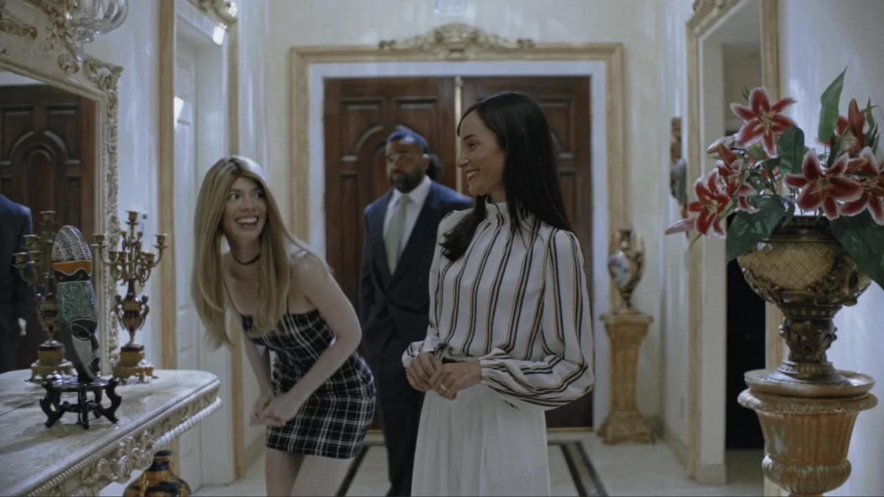 Two women at a mirror, seemingly engaged in interacting in an entryway--possibly a movie set--in Immortality.